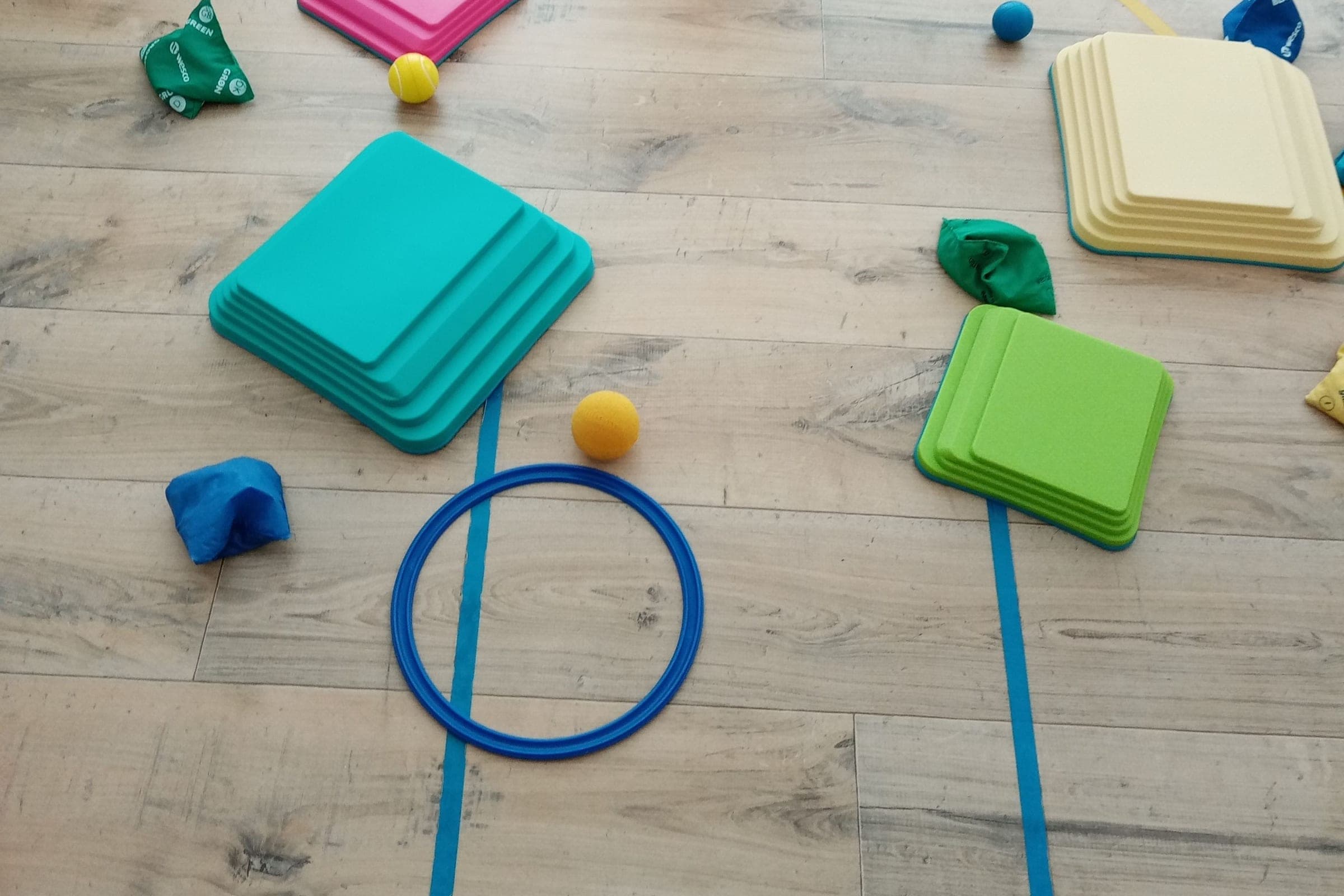 Un cerceau, des marches en mousse et des sacs lestés posés au sol pour un parcours moteur